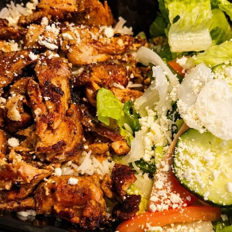 Grilled chicken and rice with a side salad topped with feta cheese in a black container.