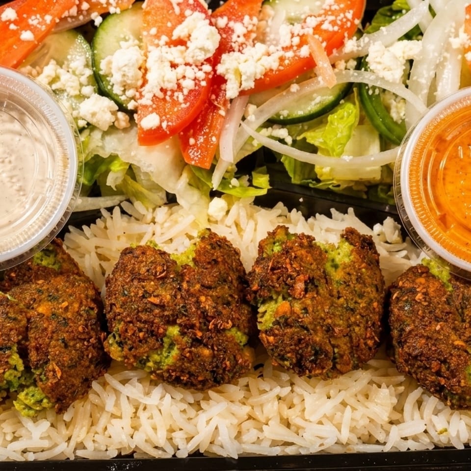 Falafel, rice, and salad with two sauces in a black takeout container on a wooden table.